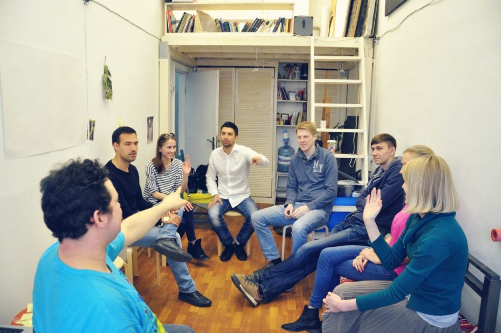 Group of people around a table playing the party game Mafia and eyeing each other with suspicion
