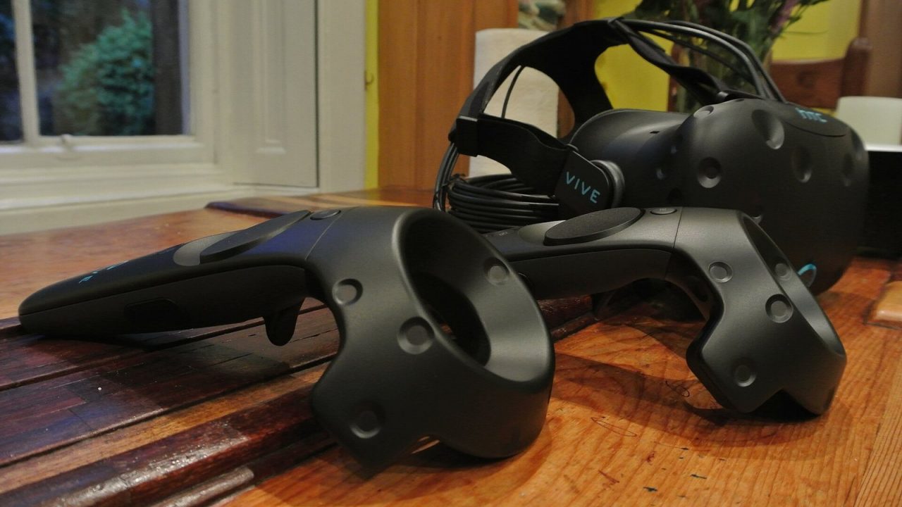 HTC Vive PC VR headset with its two wand-style motion controllers on a table